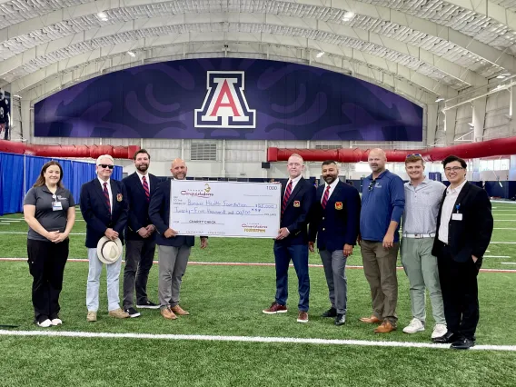 Photo of Banner Sports Medicine and Orthopedics employees and the Tucson Conquistadores holding a donation check